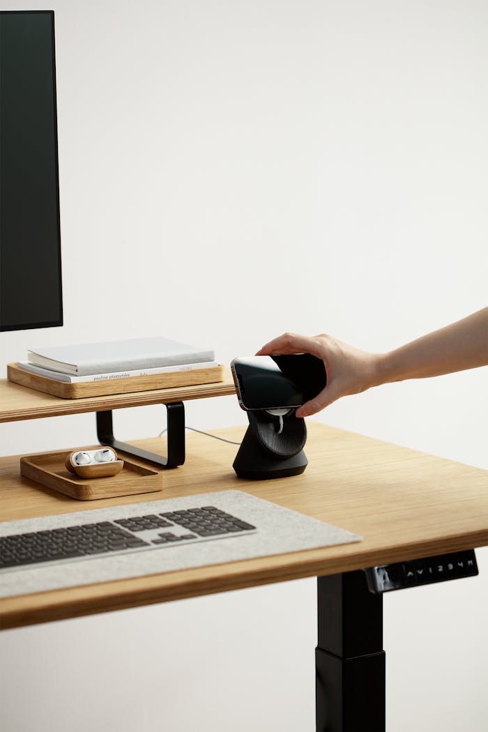 Minimalist workspace featuring a wireless charging station on an adjustable desk.